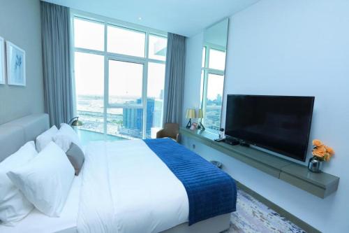 een slaapkamer met een groot bed en een grote televisie bij Damac Maison Prive Deluxe Studio with Burj-khalifa view in Dubai