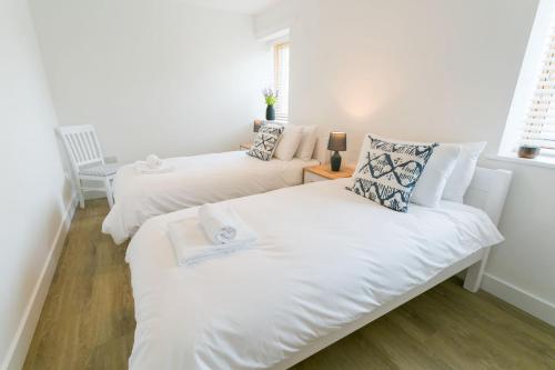 Habitación pequeña con 2 camas y paredes blancas. en Bwncath & Hebog, en Llanrhwydrys