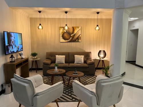 a living room with a couch and chairs and a tv at Hotel The Green Ecologic in Guarujá