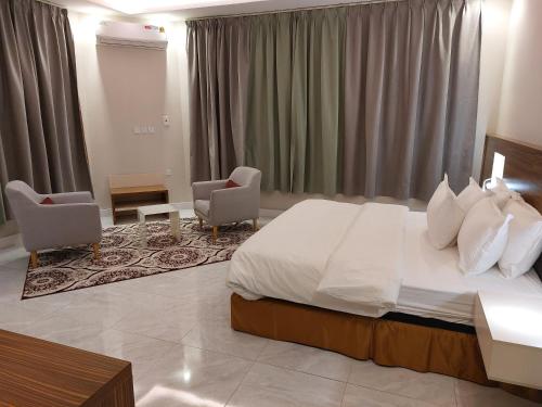 a bedroom with a large bed and two chairs at فندق تايا - Taya Hotel in Sūq al Aḩad
