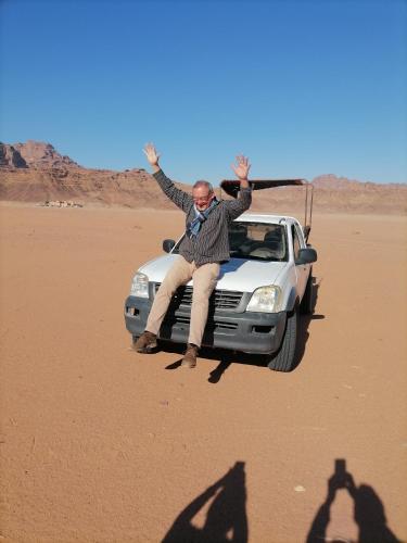 a man sitting on the hood of a car in the desert at Rum Aranda camp & Jeep Tour in Wadi Rum