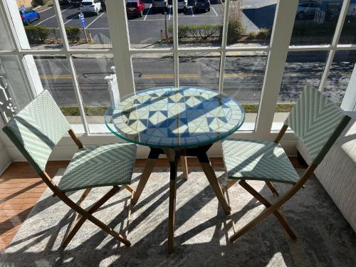 a glass table and two chairs in front of a window at Elaine's Cape May Boutique Hotel in Cape May