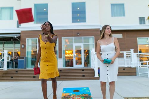 two women standing next to each other in front of a building at Compass by Margaritaville Medford in Medford