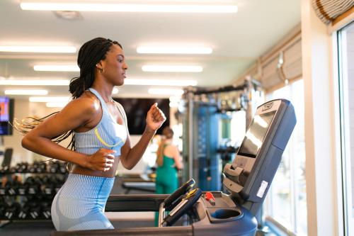 a woman running on a treadmill in a gym at Compass by Margaritaville Medford in Medford