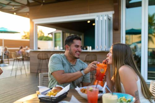 a man and a woman sitting at a table eating food at Compass by Margaritaville Medford in Medford