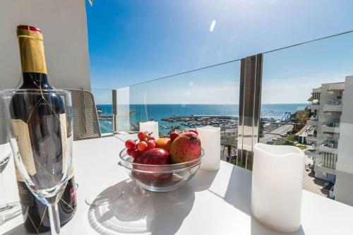 a bowl of fruit on a table with a bottle of wine at Golden Sunny View Apartment in Puerto Rico de Gran Canaria