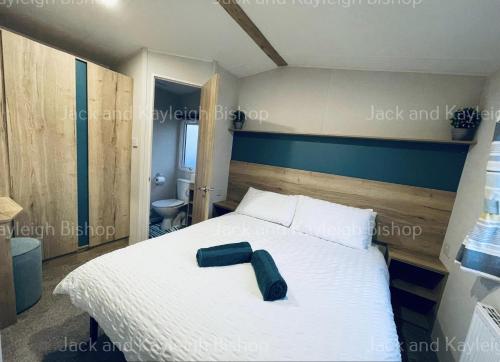 a bedroom with a white bed with a green suitcase on it at 3-Bedroom Holiday Home with Valley Views in Newquay