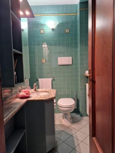 baño con lavabo, aseo y azulejos verdes en Lo sciuro, en Busto Arsizio
