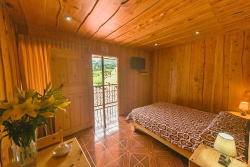 1 dormitorio con 1 cama en una habitación de madera en Hotel La Paz, en Poasito