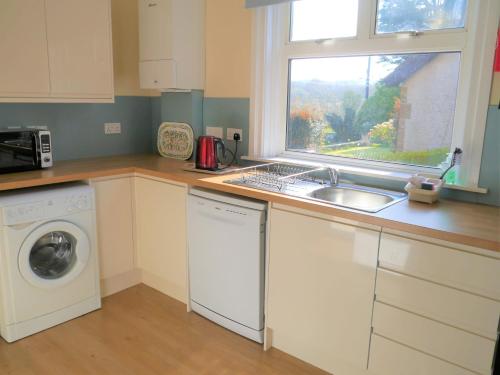 a kitchen with a sink and a washing machine at Springfield in Dalbeattie