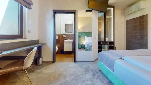 a bedroom with a bed and a desk and a bathroom at NED Hotel in Graz