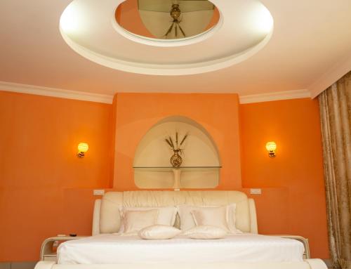 a bedroom with orange walls and a bed with a round mirror at Victory Hotel & Restaurant Tulear in Toliara