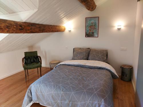 um quarto com uma cama e uma cadeira num sótão em La Treille em Tignac
