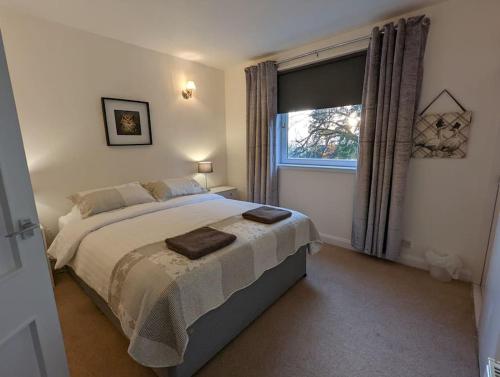 een slaapkamer met een groot bed en een raam bij Two bed flat in a quiet village near Stirling in Bridge of Allan