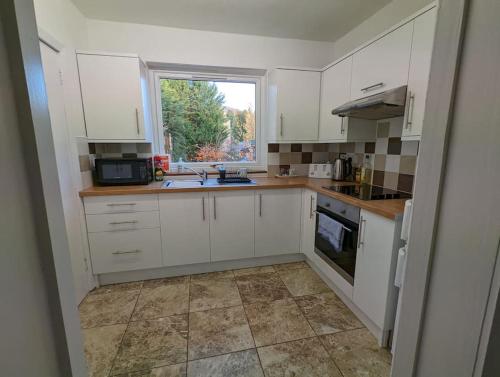 a small kitchen with white cabinets and a window at Two bedroom flat in Bridge of Allan, Stirling in Bridge of Allan