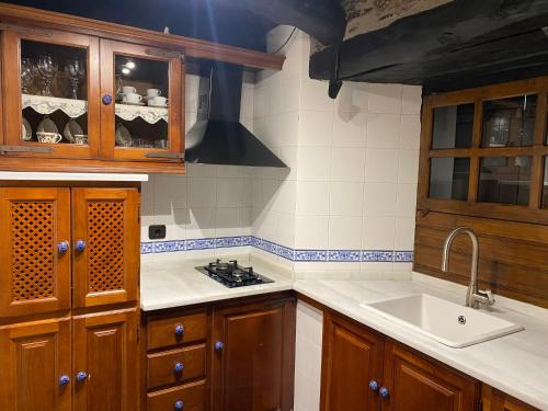 a kitchen with wooden cabinets and a sink and a stove at Casas Rurales TAReira en Taramundi in Taramundi