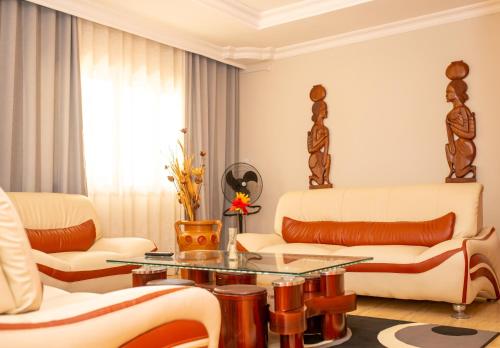 Elle comprend un salon doté d'un mobilier blanc et d'une table en verre. dans l'établissement Victory Hotel & Restaurant Tulear, à Toliara
