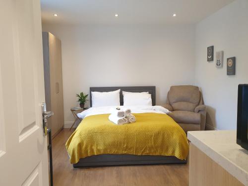 a bedroom with a bed with a yellow blanket and a chair at New - Spacious London 1 bedroom king bed apartment in quiet street near parks 1072gar in London