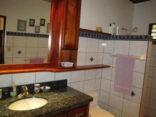 uma casa de banho com um lavatório e um espelho em Splendide villa avec piscine à 200m de l'océan. em Parrita