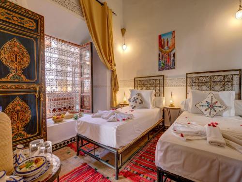 een slaapkamer met 2 bedden en een bad. bij Palais Tinmel Marrakech in Marrakesh