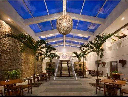 布希奧斯的住宿－Hotel Búzios Resort com Entretenimento，餐厅拥有蓝色天花板,种植了棕榈树,设有桌子