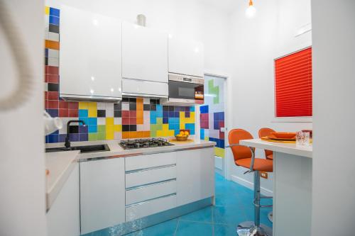 a kitchen with white cabinets and colorful tiles on the wall at Qu4ttro I Nidomare in Salerno