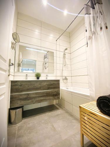 une salle de bain avec une baignoire, un lavabo et un miroir dans l'établissement Duplex cosy - entre lacs et montagnes - Fêtes interdites, à Fillinges