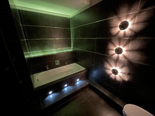 baño con bañera y luces en la pared en TruRetreats Design Loft I Riesige Küche I Wallbox I 65z SmartTV I 150qm, en Hamburgo