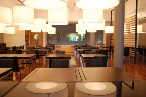 ヴァード・リーグレにあるSea Art Hotelのテーブルと椅子、シャンデリアのあるレストラン