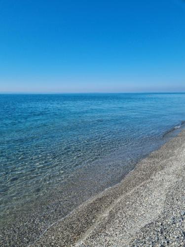 a beach with blue water and a rocky shore at VISTA MARE Su tre piani con giardino in Falerna