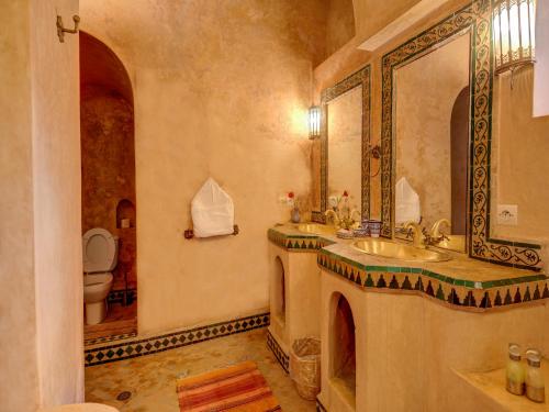 een badkamer met een wastafel, een spiegel en een toilet bij Palais Tinmel Marrakech in Marrakesh