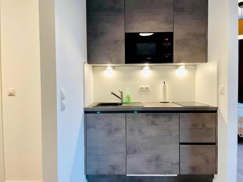 a kitchen with a sink and a microwave at Klassen Stay - Exklusives Apartment am HBF - Küche, Netflix, Kingsizebett in Koblenz