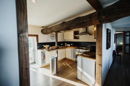 une cuisine avec des appareils blancs et un plafond en bois dans l'établissement La Bergerie Chaleureux Cottage en Bord de Mer, à Gatteville-le-Phare