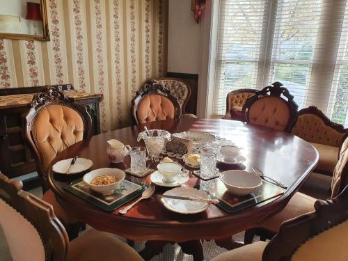 a dining room table with bowls and dishes on it at Dalkeith Boutique Bed & Breakfast in Kaiapoi