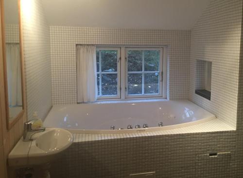 a bathroom with a tub and a sink and a window at Gålå Fjellhytte - cabin with sauna and whirlpool tub in Sør-Fron