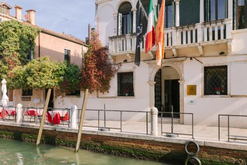 un canal frente a un edificio con banderas en el agua en Salute Palace powered by Sonder en Venecia