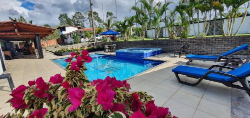 uma piscina com água azul e flores roxas em Hospedaje Campestre El Deseo em El Caimo
