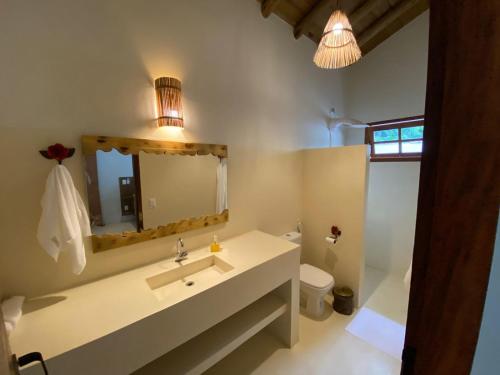 La salle de bains est pourvue d'un lavabo, d'un miroir et de toilettes. dans l'établissement Casa Harmonia, com 5 suítes em Trancoso-BA, à Trancoso