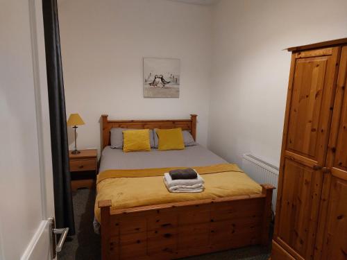 a bedroom with a wooden bed with yellow pillows at Jack's Place Beautiful 3-Bed House Donegal in Stranorlar