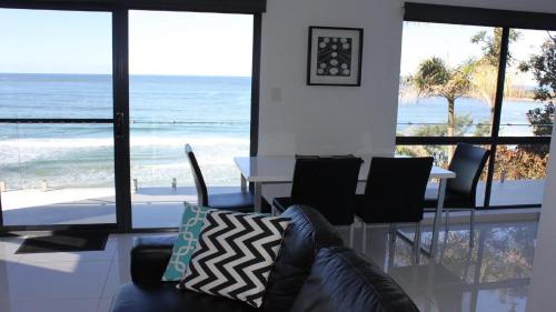 a living room with a table and chairs and the ocean at Bluefish in Yamba