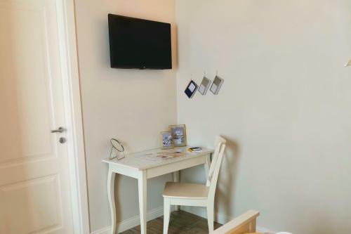 a desk with a chair and a television on a wall at Vicolo Fiore Affittacamere in Matera