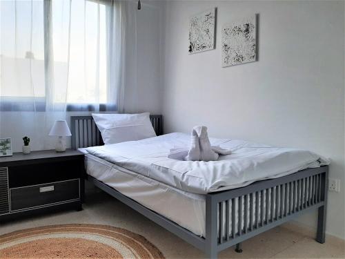 a bedroom with a bed with white sheets and a window at Royal Lovely Apartment! in Paphos City