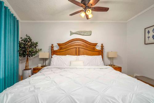 - une chambre avec un grand lit blanc et un ventilateur de plafond dans l'établissement Oceanfront Hilton Head Island Condo with Pool!, à Île de Hilton-Head