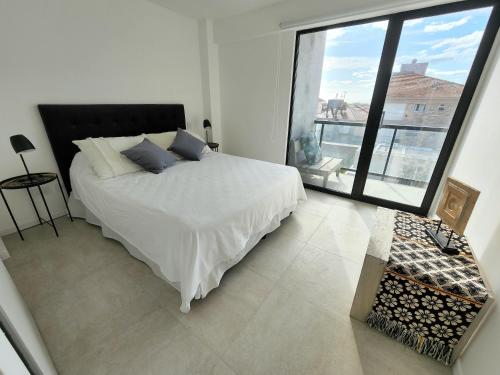 1 dormitorio con cama blanca y ventana grande en Depto premium frente al mar, cochera y piscina!! en Mar del Plata