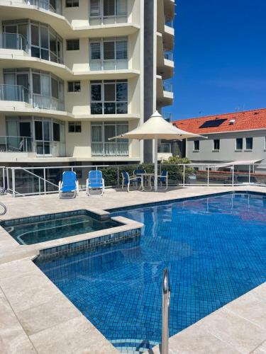a swimming pool in front of a building at Foreshore Beachfront Apartments in Gold Coast