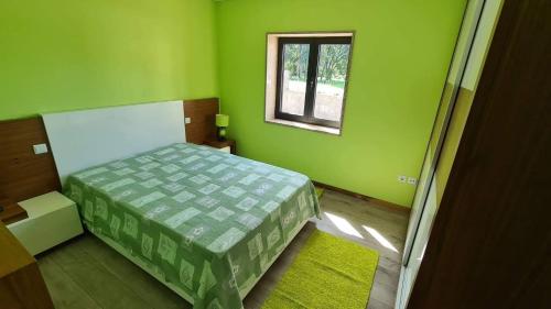 Dormitorio verde con cama y ventana en Modern Three Bedroom House en Figueiró