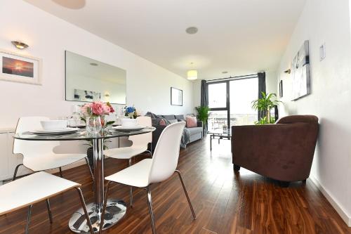 a dining room and living room with a table and chairs at Lavender House Apartments Limehouse Docklands in London
