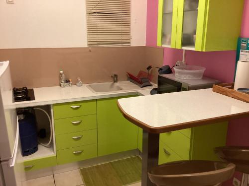 a kitchen with green and pink cabinets and a sink at Schoelcher : studio équipé, deck et vue imprenable in Schœlcher