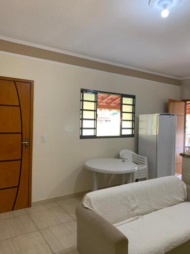 a room with a bed and a table and a refrigerator at Chácara Toca do Oliveira in Socorro