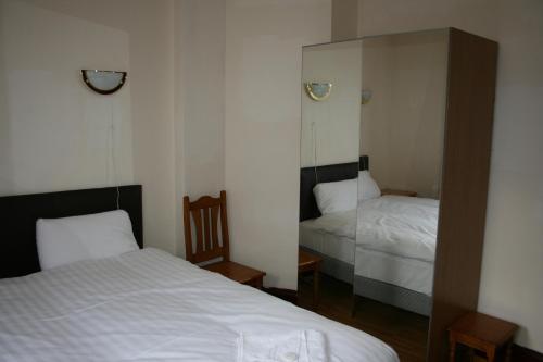 Habitación pequeña con 2 camas y espejo. en Kensington and Chelsea grand apartment, en Londres